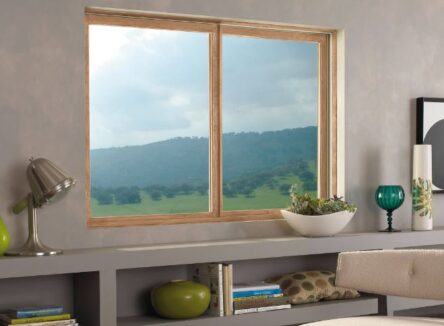 A brown glider window in a room looking at a field.
