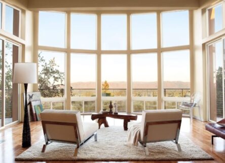 The interior of a large sitting room with floor-to-ceiling windows looking out on a prairie.
